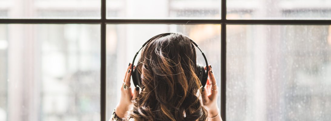 woman with headphones looking out window